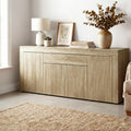 Oak buffet sideboard in living room with lamp, framed art, books and eucalyptus vase on top, jute rug on tile floor