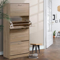 Oak 4-door flip shoe cabinet in hallway, one middle door open showing interior rack mechanism, plant and stool visible