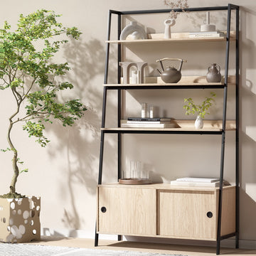 Oak and black metal ladder shelf with three open shelves above sliding door cabinet, styled with vases beside bonsai tree