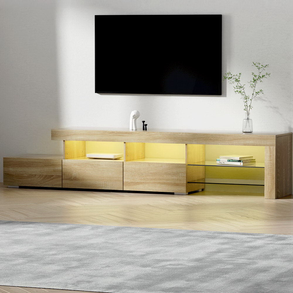 Oak finish 215cm LED TV unit in living room with yellow LED lighting in open shelves below wall-mounted TV