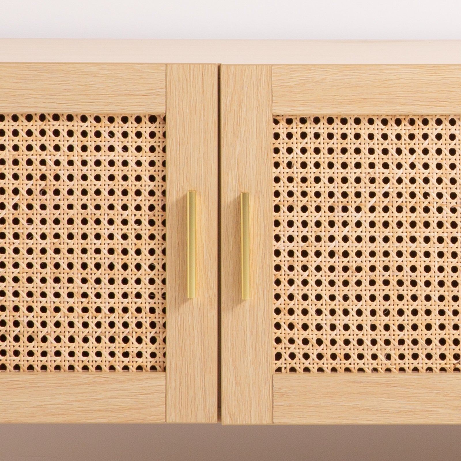 Oak and rattan TV unit close-up of two cane-weave door panels with gold bar handles on light oak frame