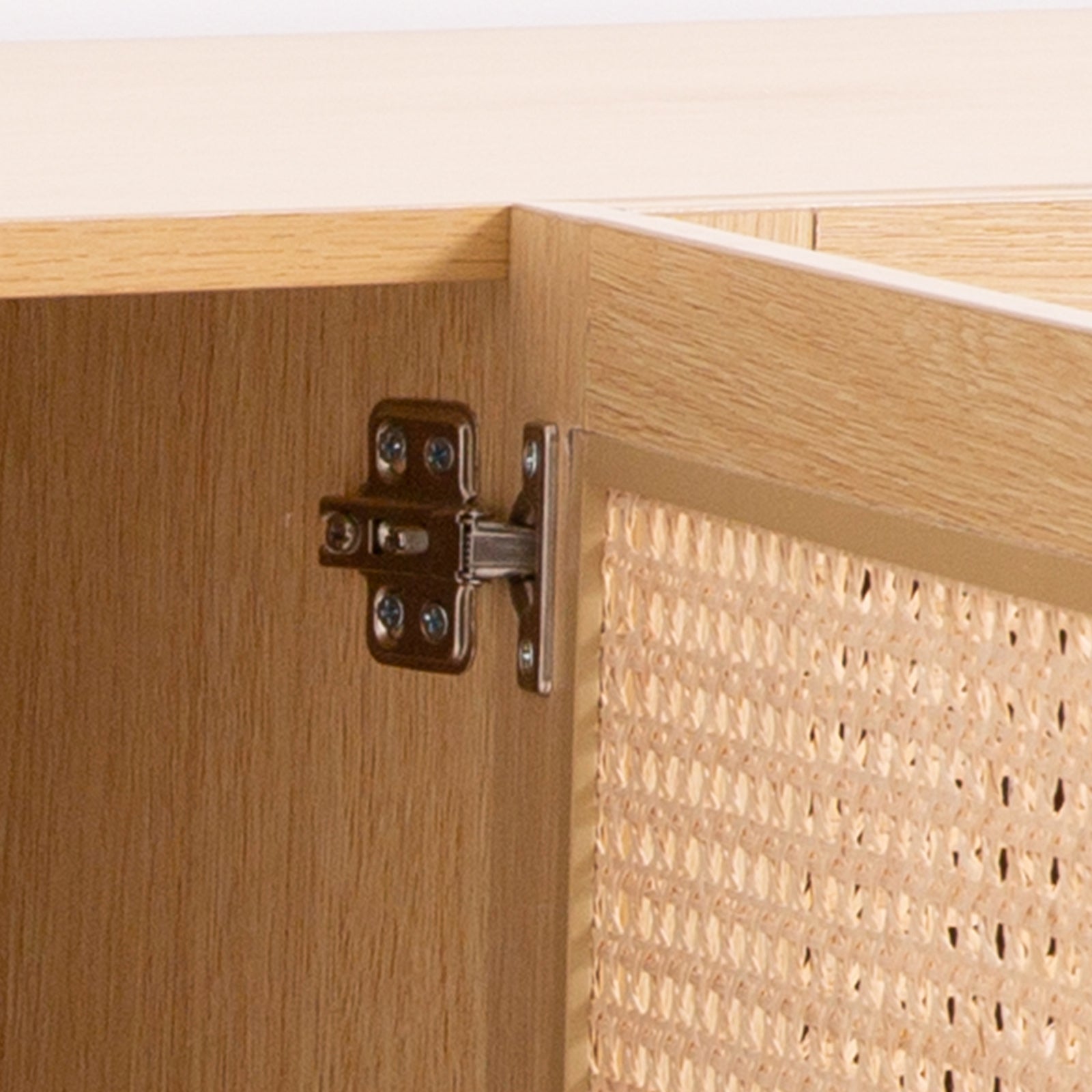 Oak and rattan TV unit interior close-up showing dark metal hinge mechanism and cane-weave door back on natural wood
