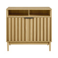 Natural oak reeded cabinet front view, two open top compartments and two lower reeded doors, black bar handles, tapered legs