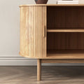 Close-up of oak reeded sideboard rounded end panel and open interior showing two shelves, tapered leg on herringbone floor