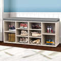 Oak shoe bench grey cushion with boots heels ballet flats and colourful sneakers in hallway with blue wall and tiled wainscot