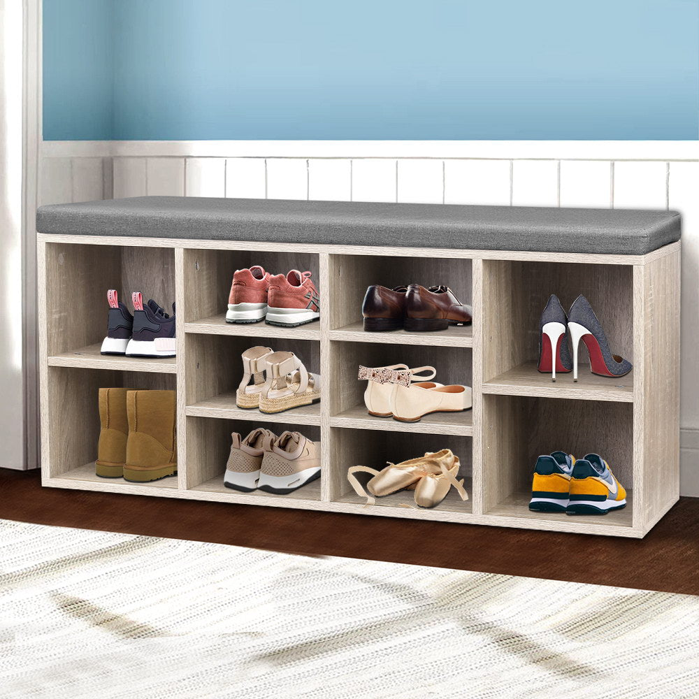 Oak shoe bench grey cushion with boots heels ballet flats and colourful sneakers in hallway with blue wall and tiled wainscot