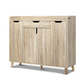 Oak finish shoe cabinet with top drawer three finger-pull handles and three lower hinged doors on natural wood cone legs