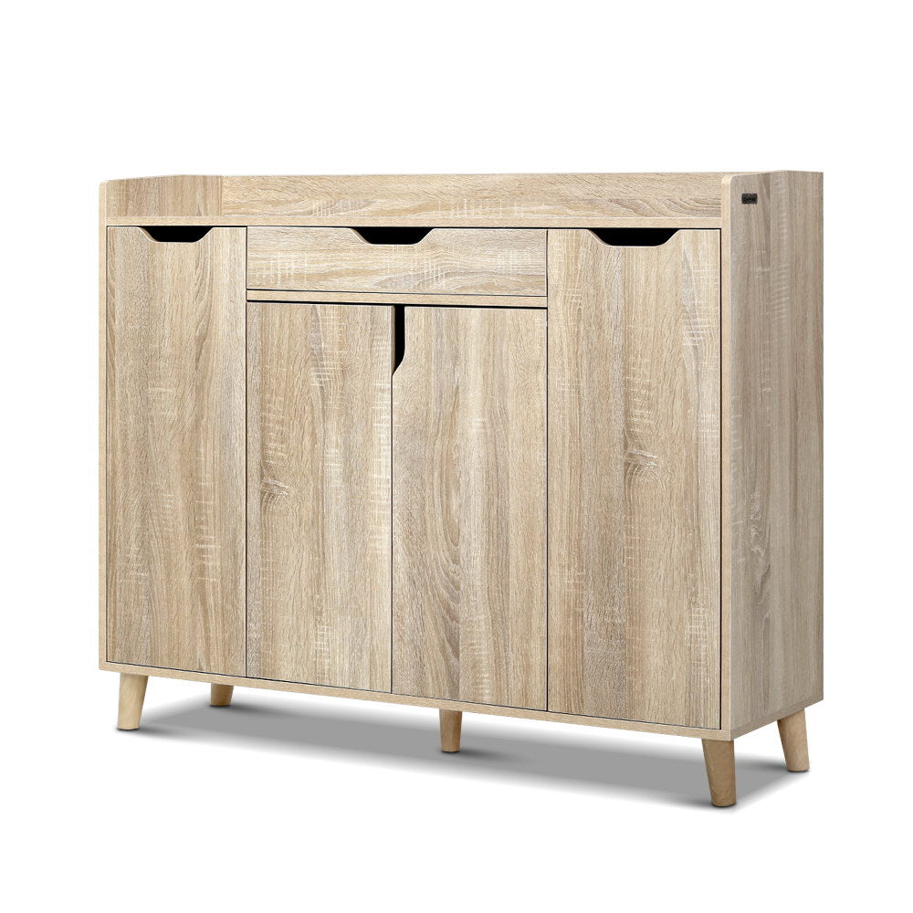 Oak finish shoe cabinet with top drawer three finger-pull handles and three lower hinged doors on natural wood cone legs