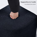 A fist pressing down into the surface of a dark navy linen ottoman top demonstrating cushion firmness