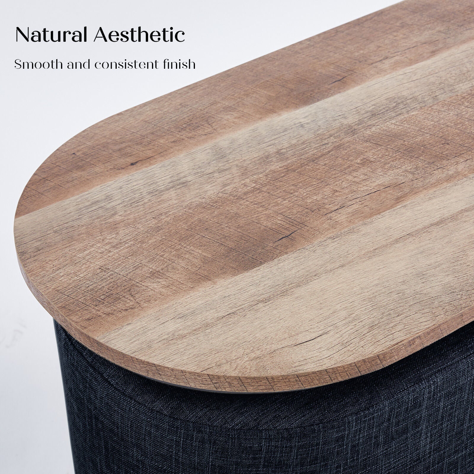 Close-up detail of an oval natural wood tabletop resting on a dark navy linen ottoman base with visible fabric texture