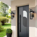 Two black rectangular framed outdoor wall lights mounted either side of a dark grey entry door on a modern house facade