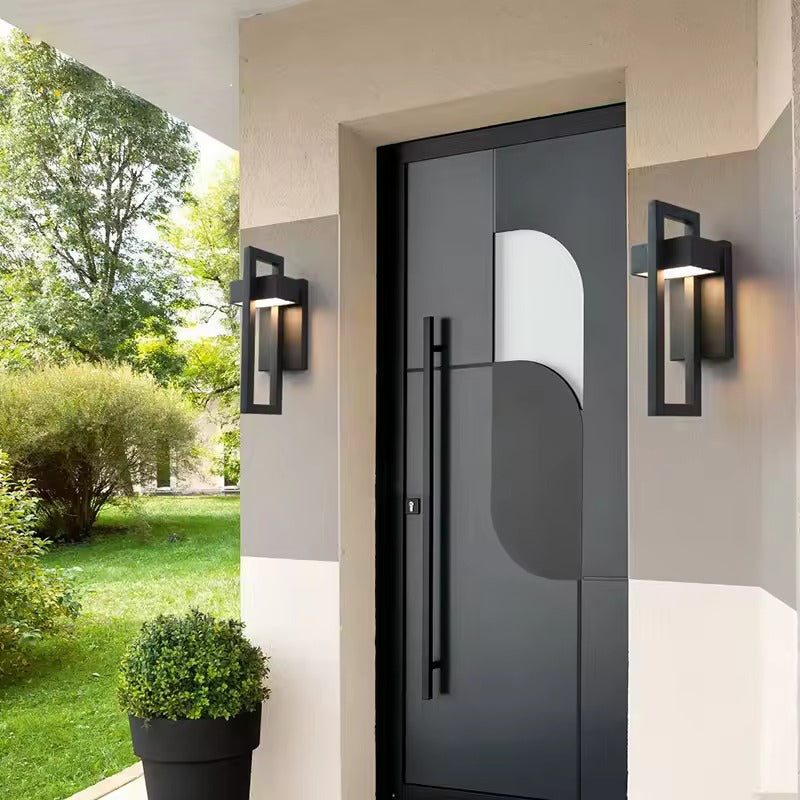 Two black rectangular framed outdoor wall lights mounted either side of a dark grey entry door on a modern house facade