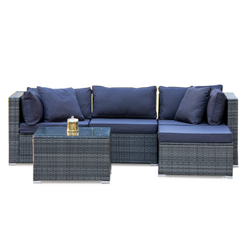 4-piece grey wicker outdoor sofa set with navy cushions and glass coffee table in L-shape configuration on white background