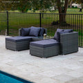 4-piece dark grey wicker outdoor sofa set with navy cushions from rear angle on stone patio beside pool, trees in background
