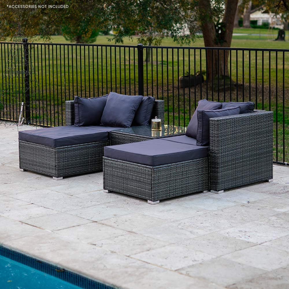 4-piece dark grey wicker outdoor sofa set with navy cushions from rear angle on stone patio beside pool, trees in background