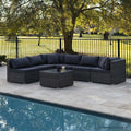 6-piece dark grey wicker sectional sofa with dark cushions in L-shape beside pool on stone patio, trees behind fence