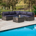 5-piece grey wicker outdoor sofa set with navy cushions in L-shape beside swimming pool on stone patio