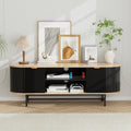 Oval oak-top black fluted TV unit 140cm lifestyle in white room with art prints lamp plant and gaming items on center shelves