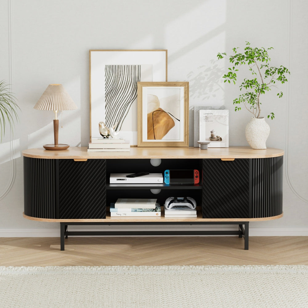 Oval oak-top black fluted TV unit 140cm lifestyle in white room with art prints lamp plant and gaming items on center shelves