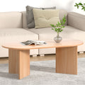 Oval natural wood coffee table with T-panel legs, styled with magazine and vase, cream sofa in background