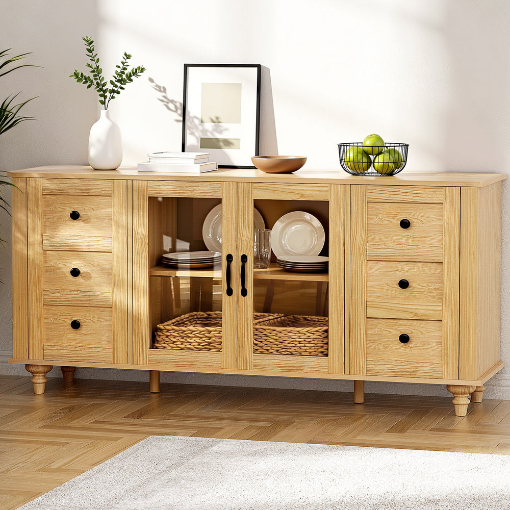 Pine sideboard in room with glass doors open showing dishes and baskets inside, vase, frame and fruit bowl on top