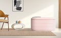 Pink fabric storage ottoman on beige rug in living room with mustard chair, abstract wall art and magazine on lid
