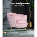 Pink velvet scallop shell armchair with gold legs in dark moody room beside tall plant in gold pot, Enamoured presence text