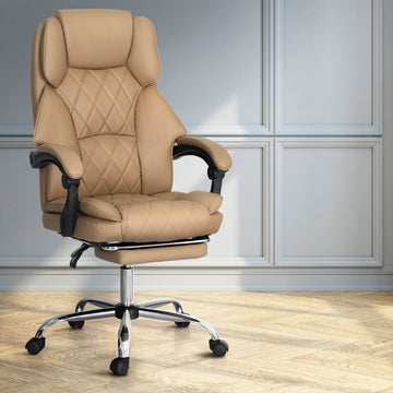 Tan PU leather diamond-stitch high-back executive chair with chrome base in lifestyle room with grey panelled walls