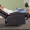 Woman lying fully reclined in dark brown PU leather recliner with footrest extended and swivel tray deployed