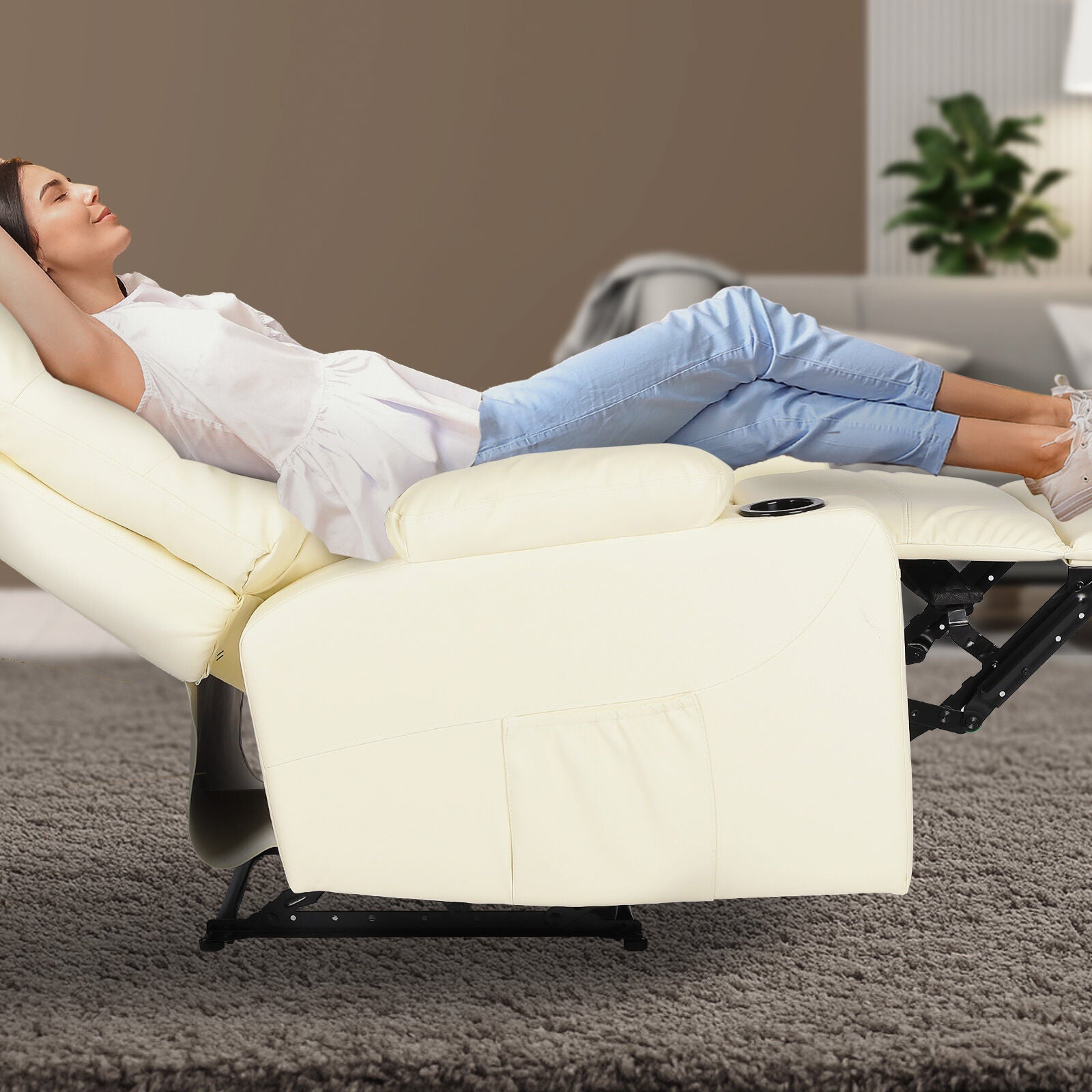 Woman fully reclined in cream tufted PU leather recliner with footrest extended and cup holder, living room setting