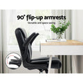 Black PU mid-back chair side view with 90-degree flip-up armrests raised next to white desk, 90-degree arc circle inset