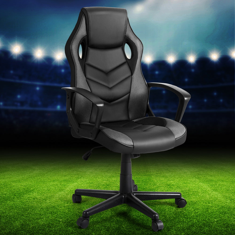 Black and grey PU mesh racing-style gaming chair angle view on stadium football pitch lifestyle background