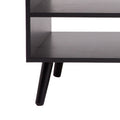Close-up detail of black coffee table showing two open shelves and black tapered wooden legs on white background