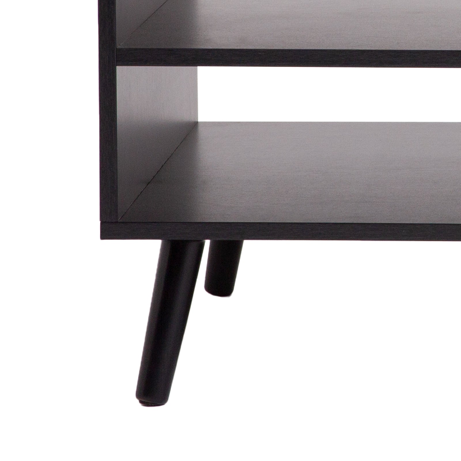 Close-up detail of black coffee table showing two open shelves and black tapered wooden legs on white background