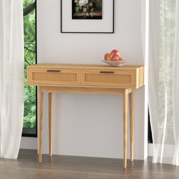 Oak console table with two rattan-weave drawers and black bar handles on tapered legs, styled with fruit bowl in room