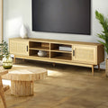 Rattan TV stand 180cm in living room below wall-mounted TV with rattan round coffee table and tropical plants