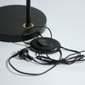 Black round floor lamp base with black cord, oval foot switch and Australian three-pin plug on white surface