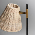 Close-up of woven rattan lampshade tilted on brass pivot connector with black pole, showing intricate weave texture