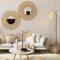 Rattan floor lamp with tilted conical shade beside cream sofa in bohemian living room with round wicker wall mirrors