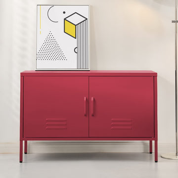 Red metal two-door locker cabinet with vent slots on thin legs in living room setting with geometric art print on top