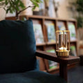 Gold retro lantern LED lamp glowing on wooden armrest of teal armchair with bookshelf in background