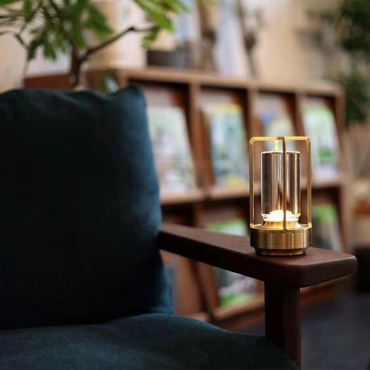 Gold retro lantern LED lamp glowing on wooden armrest of teal armchair with bookshelf in background