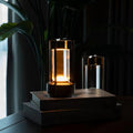 Black retro lantern LED lamp glowing on stacked books with Radio Astronomer title, second lamp and plant in background
