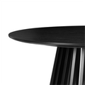 Close-up of the edge and slatted base junction of a black round coffee table showing the rounded tabletop profile and