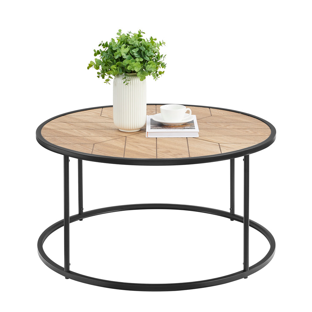 Round oak sunburst coffee table styled with white vase of greenery, coffee cup and book, white background