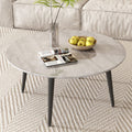 Round marble-effect coffee table viewed from above with open magazine, fruit bowl and glass vase on woven rug