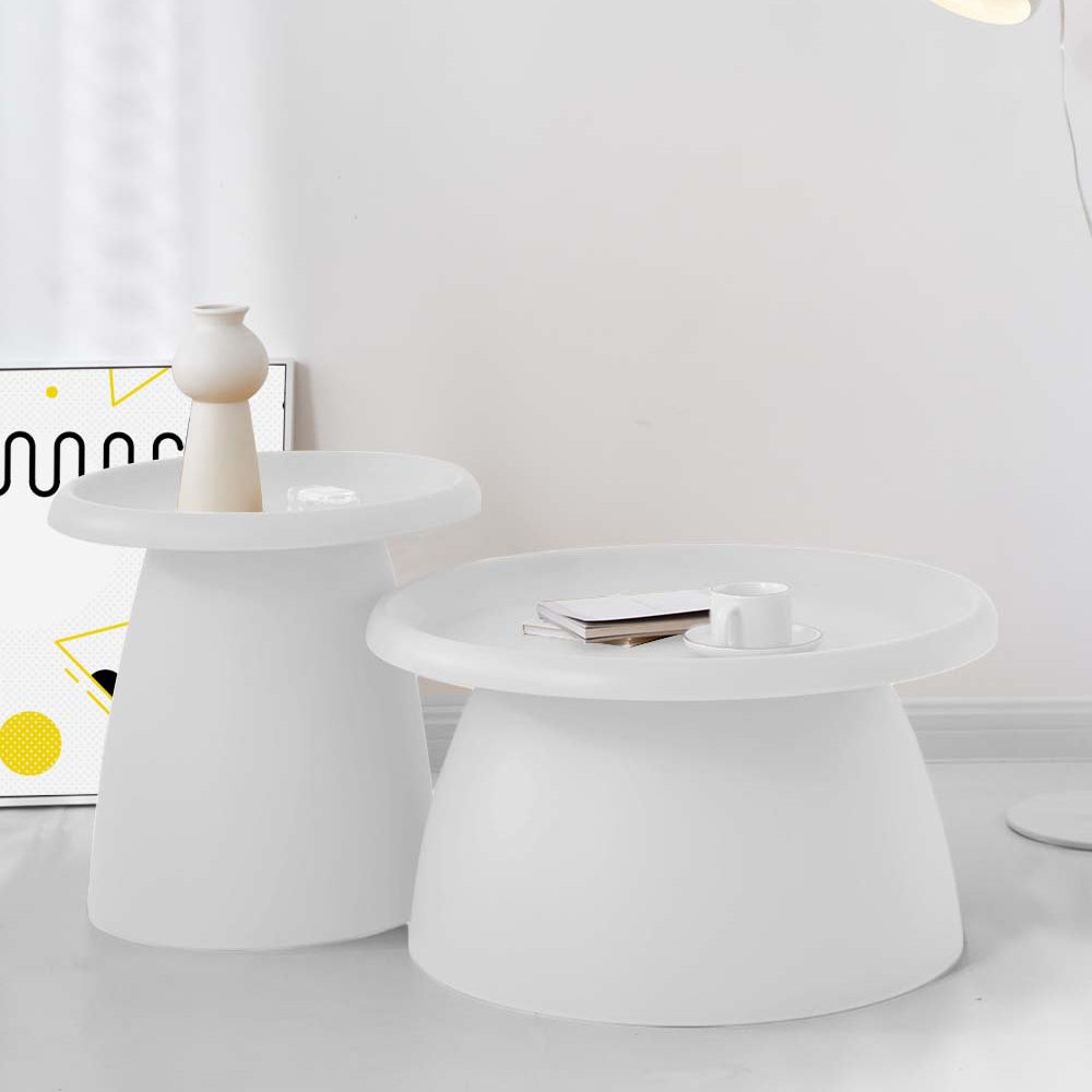 Two round white tray-top coffee tables of different sizes displayed together, one with a vase and one with a book and cup,