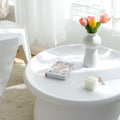 Top-down view of a round white tray-top coffee table styled with a vase of flowers, a book titled Connect Every Day, and a