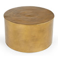 Cylindrical hammered brass-finish metal coffee table three-quarter angle view showing hammered dot texture across top and