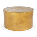 Close-up of the top edge of a cylindrical hammered brass-finish metal coffee table showing concentric dimple texture and